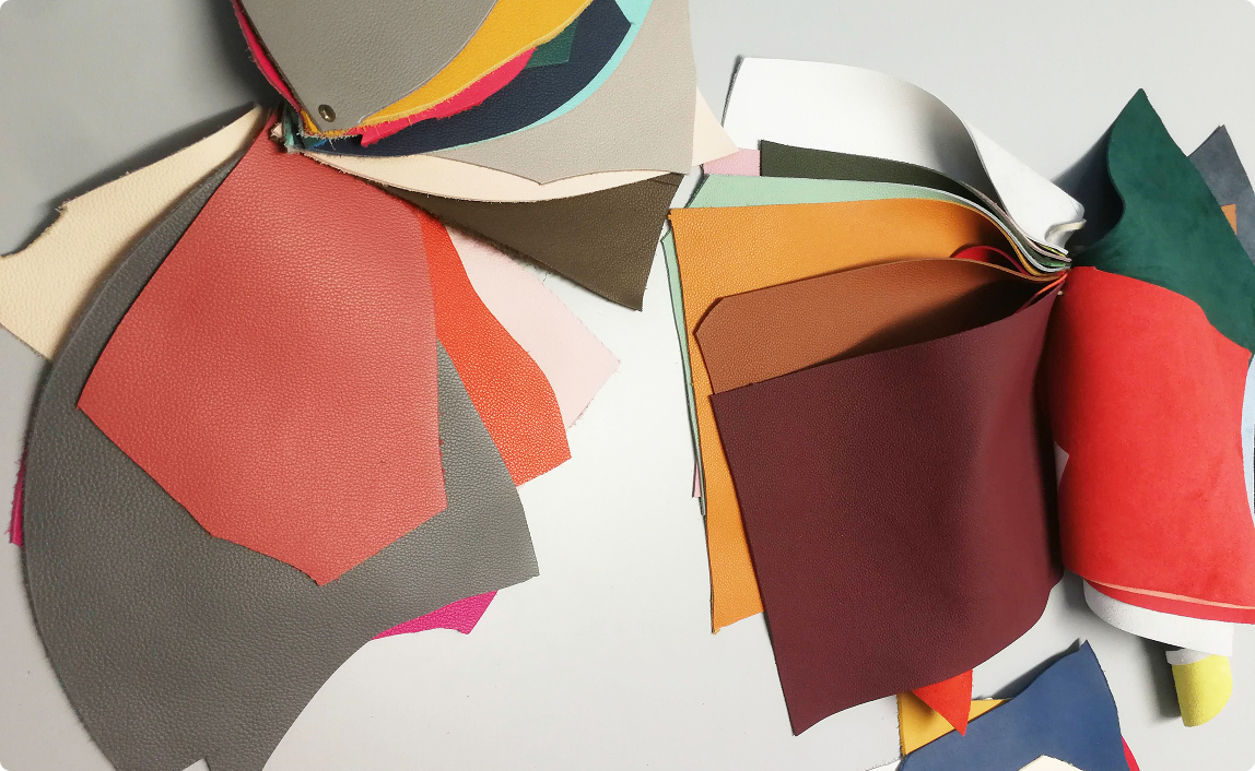 Assorted leather color swatches arranged on a table, showcasing different textures and shades used in handbag design.