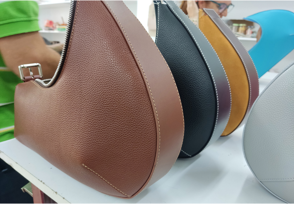 Leather bag design templates with golden metal logo pieces placed on top of the pattern sheets.