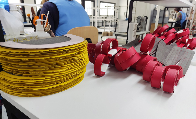 Stacks of yellow and red leather components organized on a workshop table ready for assembly.